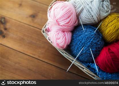 handicraft and needlework concept - close up of wicker basket with knitting needles and balls of yarn. basket with knitting needles and balls of yarn