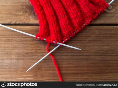 handicraft and needlework concept - hand-knitted item with knitting needles on wood. hand-knitted item with knitting needles on wood