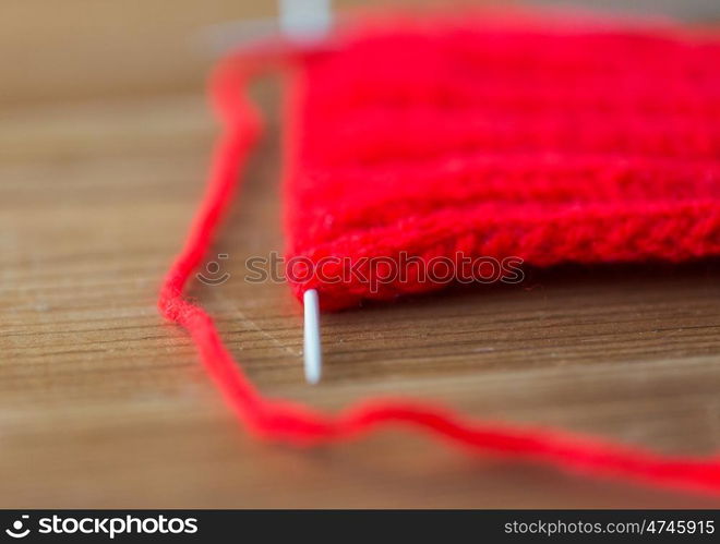 handicraft and needlework concept - hand-knitted item with knitting needles on wood. hand-knitted item with knitting needles on wood