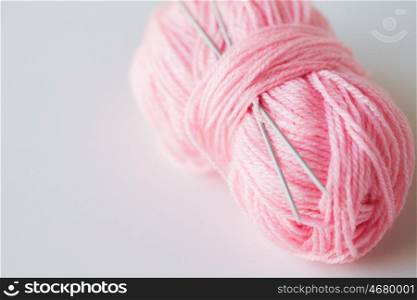 handicraft and needlework concept - knitting needles and ball of pink yarn on white. knitting needles and ball of pink yarn