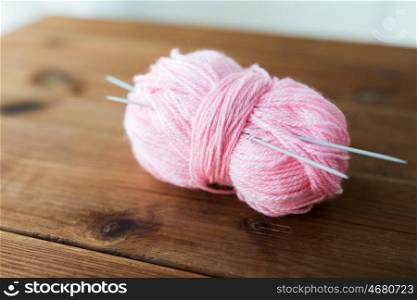 handicraft and needlework concept - knitting needles and ball of pink yarn on wood. knitting needles and ball of pink yarn on wood