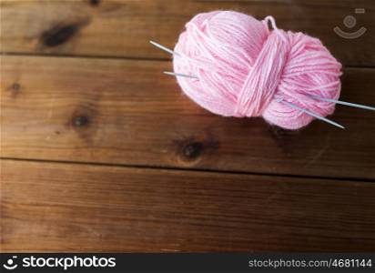handicraft and needlework concept - knitting needles and ball of pink yarn on wood. knitting needles and ball of pink yarn on wood