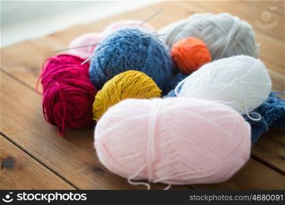handicraft and needlework concept - knitting needles and balls of yarn on wood. knitting needles and balls of yarn on wood
