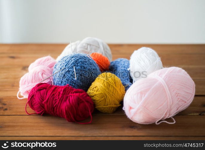 handicraft and needlework concept - knitting needles and balls of yarn on wood. knitting needles and balls of yarn on wood