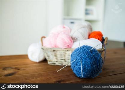 handicraft and needlework concept - wicker basket with knitting needles and balls of yarn. basket with knitting needles and balls of yarn