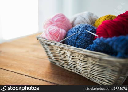 handicraft and needlework concept - wicker basket with knitting needles and balls of yarn. basket with knitting needles and balls of yarn