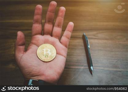 Handle of Bitcoin coin and pen on wooden floor background.