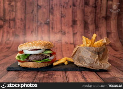 Handmade burger with fries on wooden background