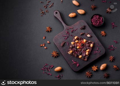 Handmade chocolate with berries, nuts and spices on a dark concrete background. Sweets made at home