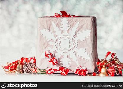 Handmade Christmas gift box with paper snowflakes and red decorations on bokeh background, front view