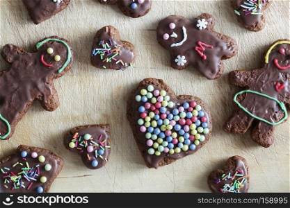 Handmade decorated gingerbread heart and people figures lying on wooden table. Christmas, Valentines Day, love symbol.