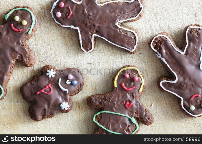Handmade decorated gingerbread people lying on wooden table. Christmas
