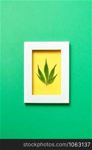 Handmade decorative rectangular frame with green fresh marijuana leaf on a green background, copy space. Concept use of cannabis for medical puposes. Flat lay.. Creative yellow handmade frame with cannabis leaf on a green background.