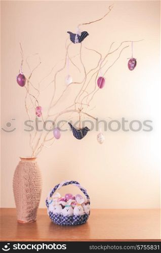 Handmade easter decorations on the branches in vase and textile basket. Handmade easter decorations