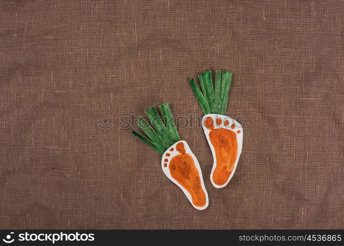 handmade foot-shaped carrot on sackcloth background. handmade foot-shaped carrot