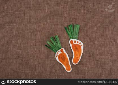 handmade foot-shaped carrot on sackcloth background. handmade foot-shaped carrot