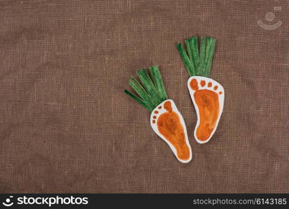 handmade foot-shaped carrot on sackcloth background. handmade foot-shaped carrot