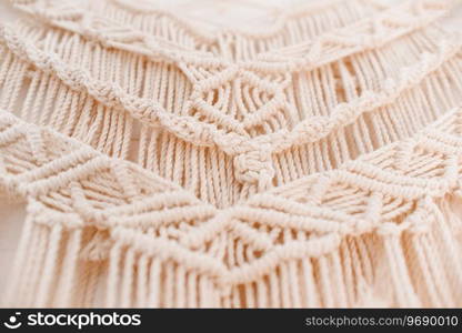handmade macrame pattern a fragment of a wall panel in the boho style of beige cotton threads of natural color using the technique for home and wedding decor