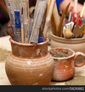 Handmade old clay pots with pencils and other stuff on the table