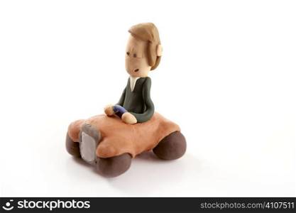 Handmade plasticine man driving a car isolated on white
