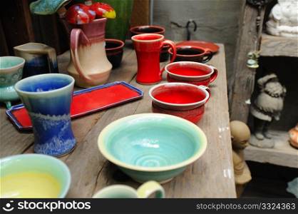 Handmade pottery on display in a rustic setting, vases, cups, bowls and other ceramic items.