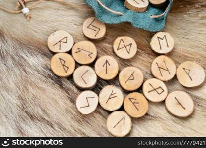 Handmade runes for fortunetelling in leather bag over wolf fur. Handmade runes for fortunetelling