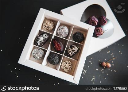 handmade sugar free and gluten free fruit and chocolate candies in a white box and black background. handmade fruit and chocolate candies in a white box