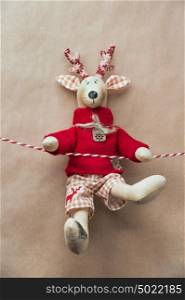 Handmade vintage Christmas deer hanging on a ribbon on grunge old natural colored paper background