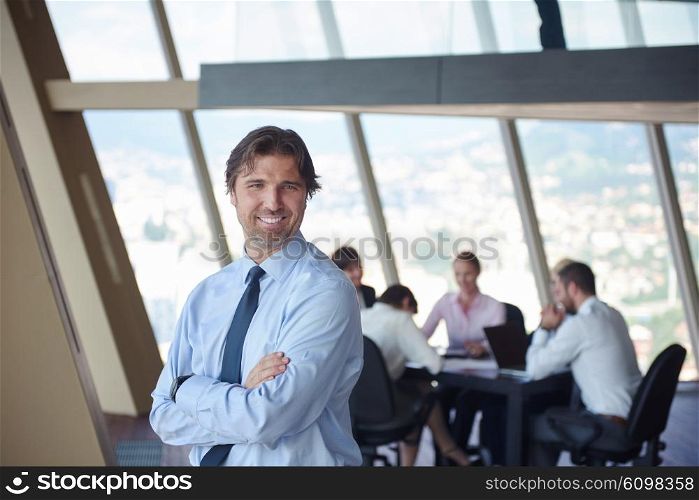 handosme business manportrait at modern bright office indoors with his team in group working together in background