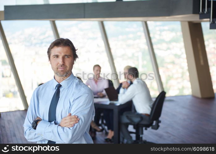 handosme business manportrait at modern bright office indoors with his team in group working together in background