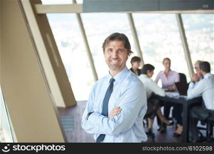 handosme business manportrait at modern bright office indoors with his team in group working together in background