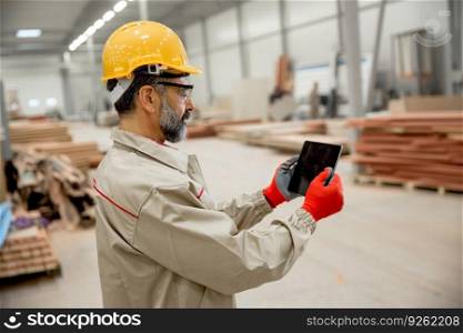 Handosme engineer with helmet controlling works in factory with digital tablet