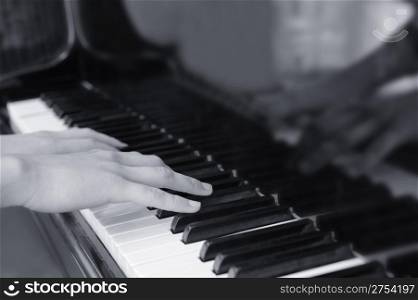 Hands above keys of the piano. A photo close up.Monochrome tone