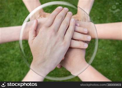 Hands arms above grass uniting joining in glass sphere