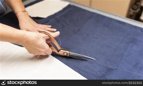 hands cutting material with scissors close up
