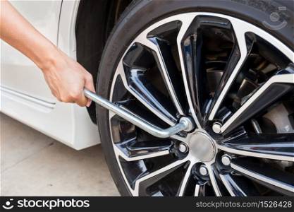 Hands disassembling a modern car wheel (steel rim) with a lug wrench for change wheel