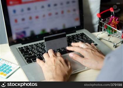 Hands holding a credit card and using a laptop computer on the table