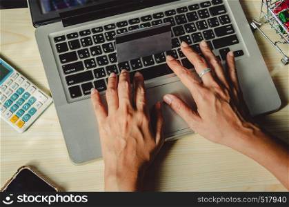 Hands holding a credit card and using a laptop computer on the table
