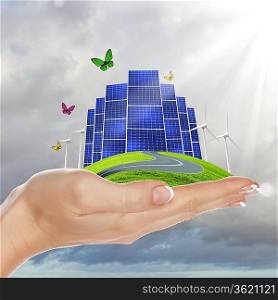 Hands holding a green earth with solar batareis