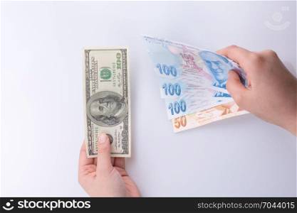 Hands holding American dollar banknotes and Turksh Lira banknotes side by side on white background