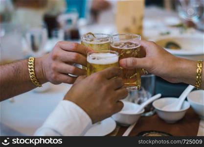 Hands holding beer glasses for celebration in the party