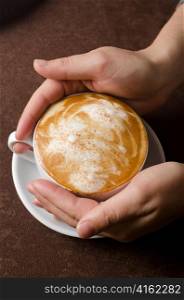 Hands holding cup of cappuccino