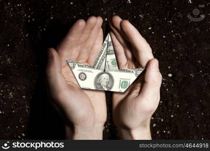 Hands holding dollar banknote ship and soil at background . Rich soil for your income