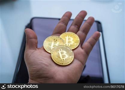 Hands holding Golden bitcoins or cryptocurrency coin or symbols on digital tablet in white table. Future currency concept.