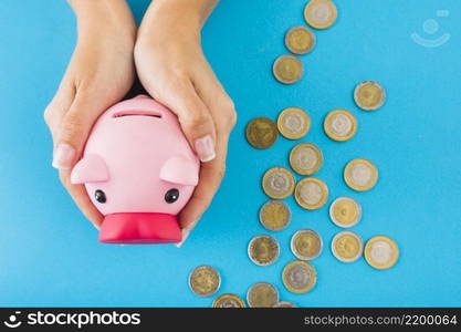 hands holding piggy bank table with coins