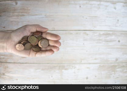 Hands holding pile of money euro coins in hand on wood background. Donation, saving, fundraising charity, family finance plan concept, financial crisis concept. Top view. copy space space for text. Hands holding pile of money euro coins in hand on wood background. Donation, saving, fundraising charity, family finance plan concept, financial crisis concept. Top view. copy space