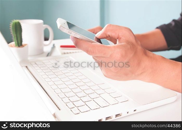 Hands holding smartphone and using laptop. Officer and business concept