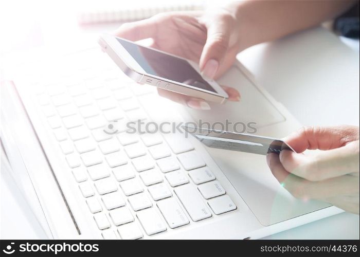 Hands holding smartphone, credit card and using laptop. Online shopping