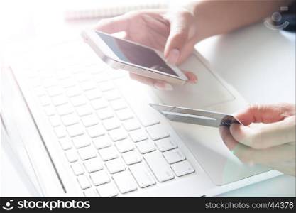 Hands holding smartphone, credit card and using laptop. Online shopping