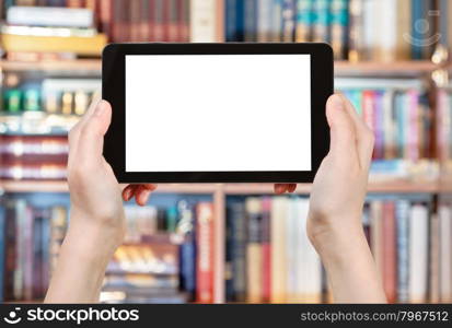 hands holding tablet pc with cut out screen in front od books library